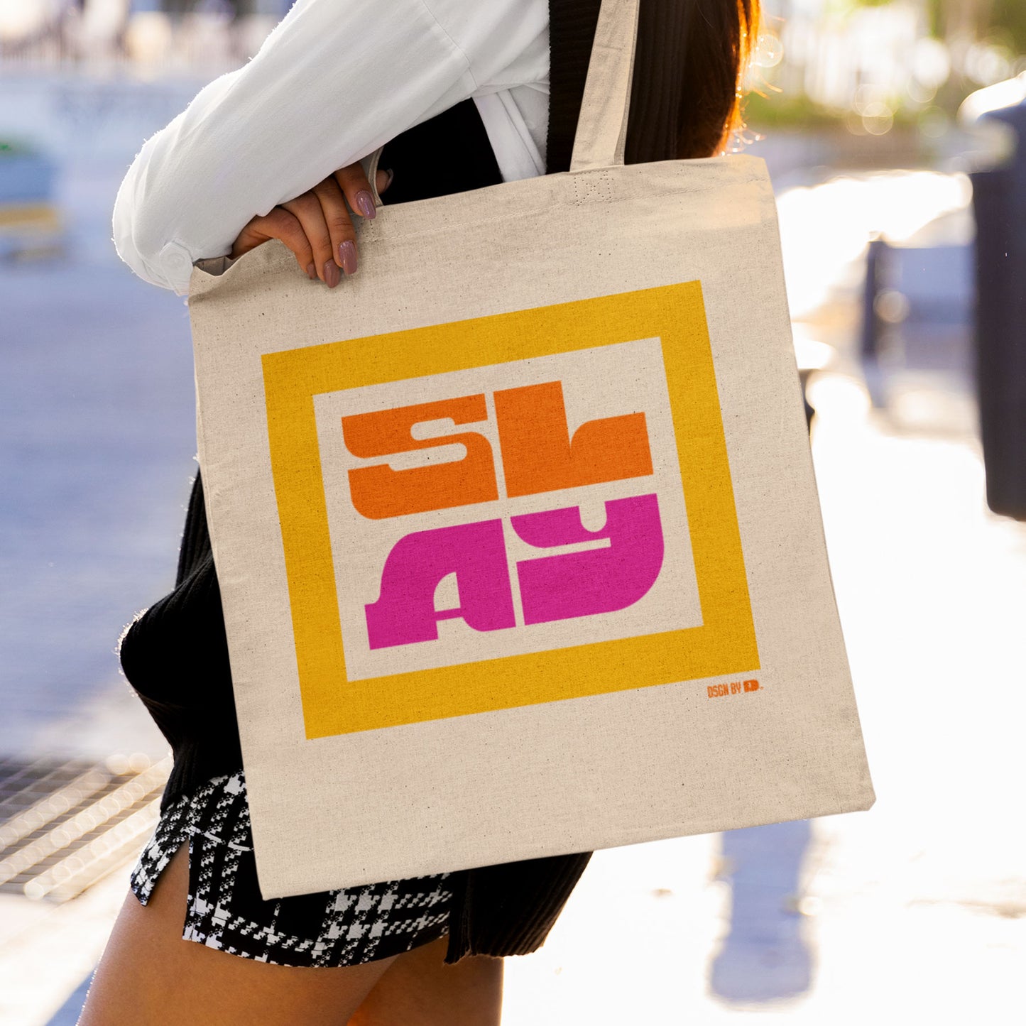 A woman carrying cotton canvas tote bag with yellow, orange, and pink design.