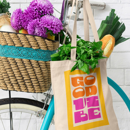A Good Vibe tote bag hanging on a bicycle.