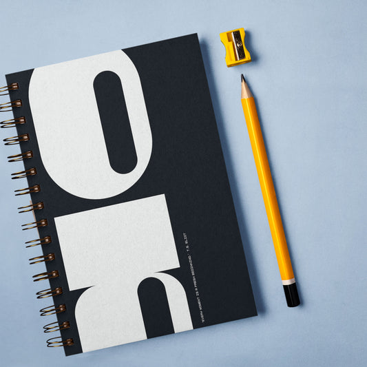 A black cover notebook next to a pencil.
