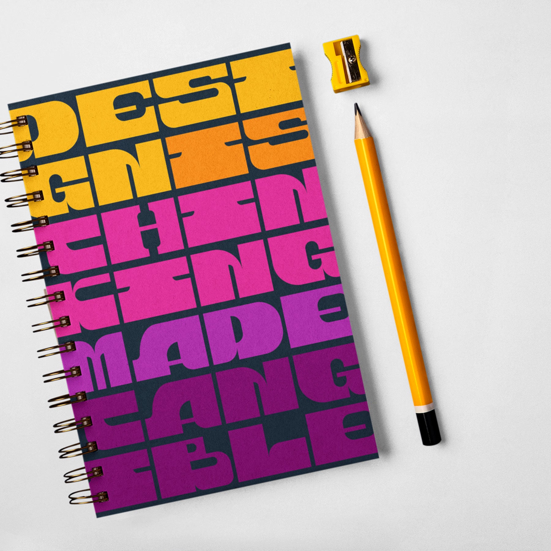 A colorful spiral bound notebook with yellow, pink, and purple typography.