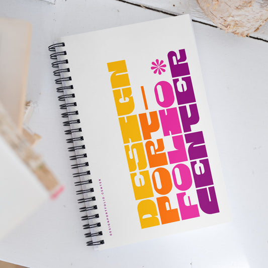 White notebook with colorful cover showing yellow, orange, pink, and purple typography.